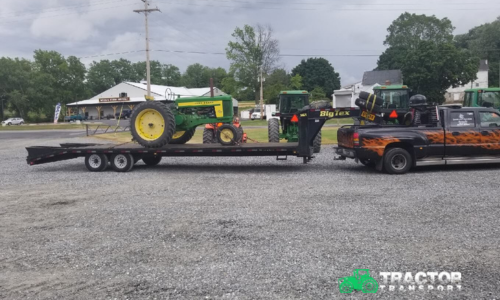John Deere tractor and spare agricultural tires loaded on lowboy trailer for heavy equipment transport
